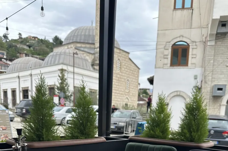 View from a Rustemi window table: domes, a stone tower and cypress trees in Berat