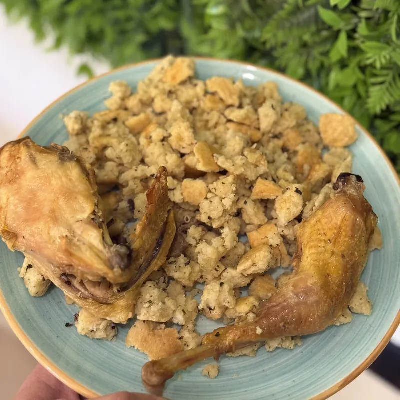 Roast chicken with toasted bread pieces on a teal plate