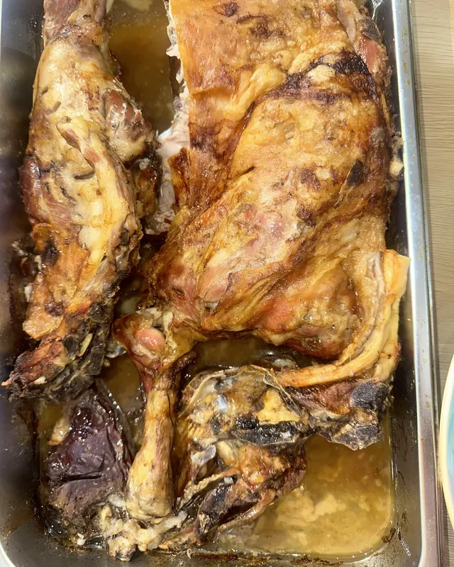 Roast lamb in a baking tray, the skin crisp and browned