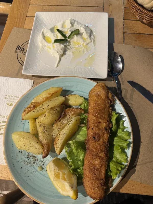 A grilled meat roll with oven potatoes and lemon, with sour cream on the side